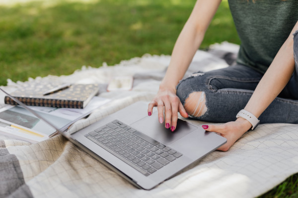 Student on campus grounds looking at laptop: Photo by Karolina Grabowska from Pexels